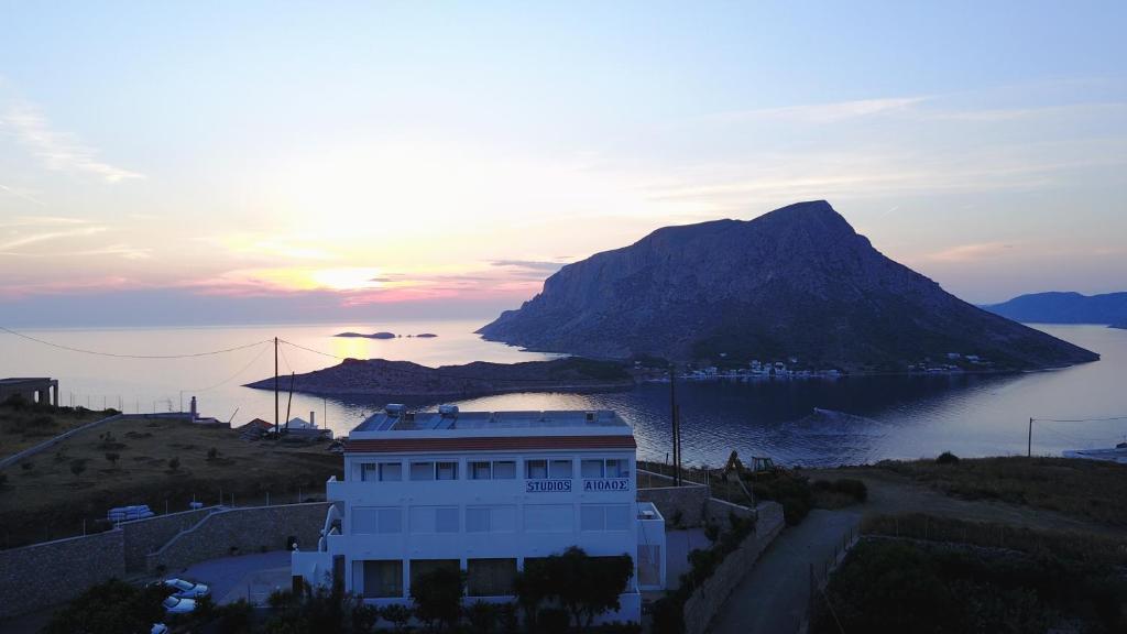 a building with a mountain in front of a body of water at Studios Aeolos Kalymnos in Myrties