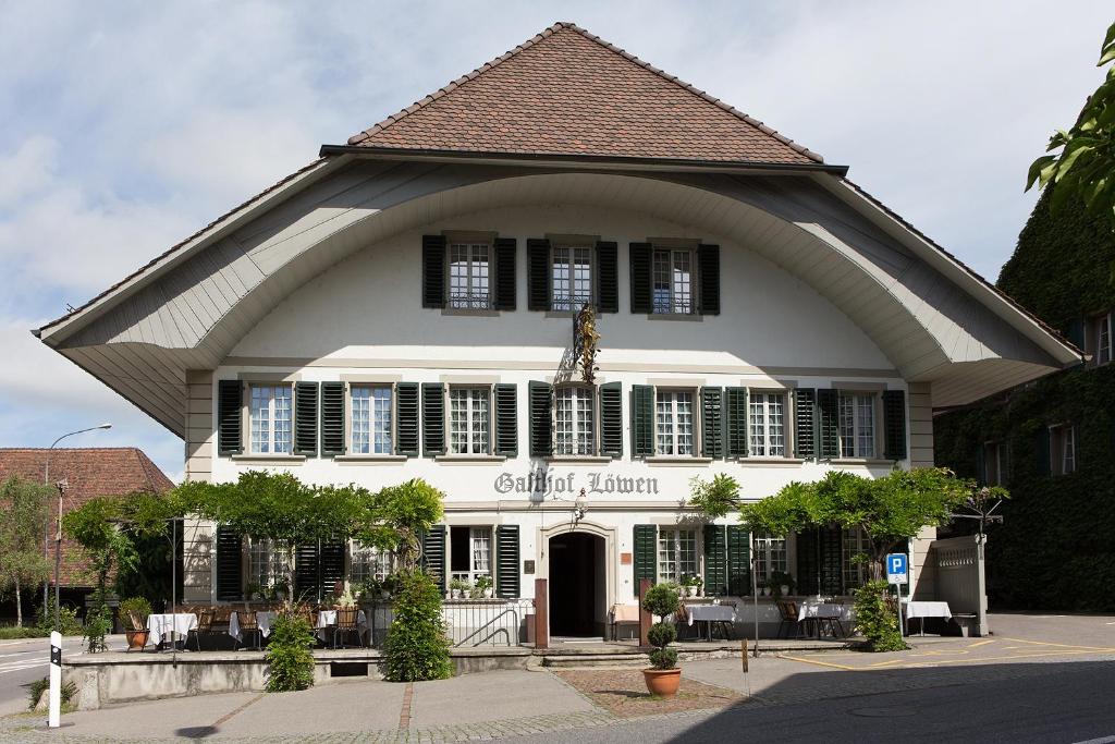 um grande edifício branco com um telhado de gambrel em Gasthof Löwen Worb bei Bern em Worb