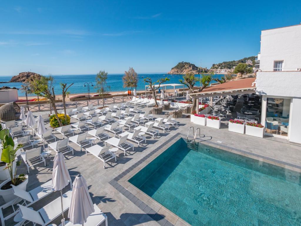 
a beach area with a pool, chairs, and tables at Golden Mar Menuda in Tossa de Mar
