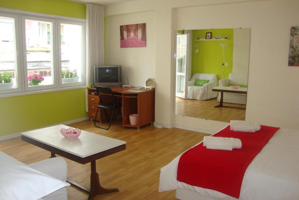a bedroom with a bed and a desk and a living room at Guest Rooms Colours in Kazanlŭk