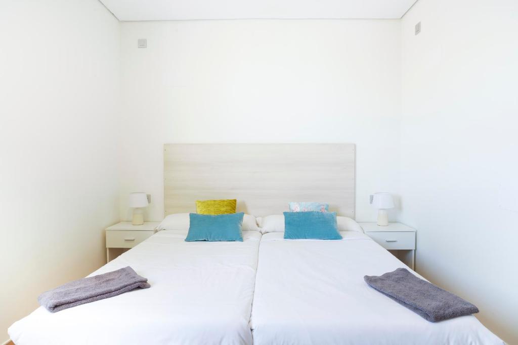 2 camas en un dormitorio con almohadas azules y amarillas en Koisi Hostel, en San Sebastián