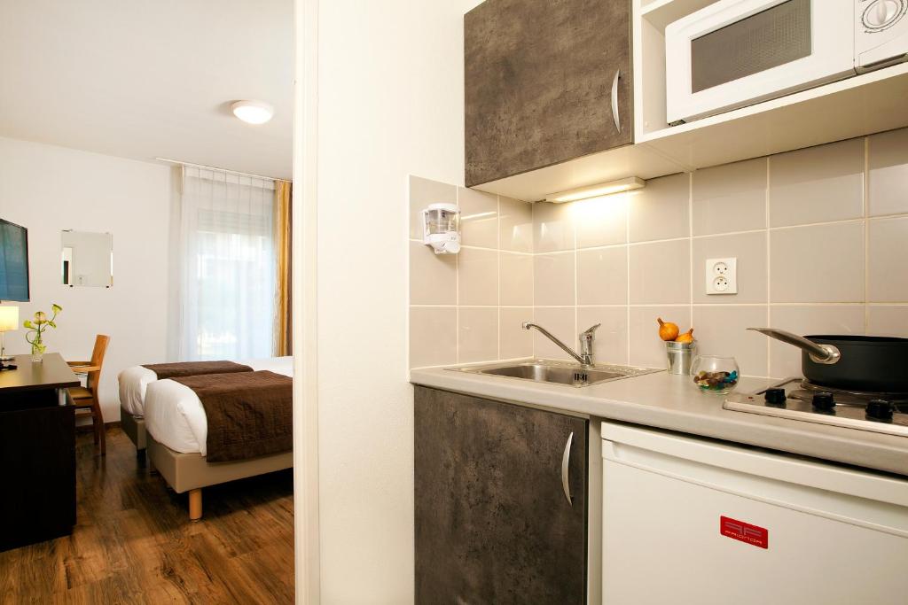 cocina con fregadero y habitación con cama en Séjours & Affaires Caen Le Clos Beaumois en Caen