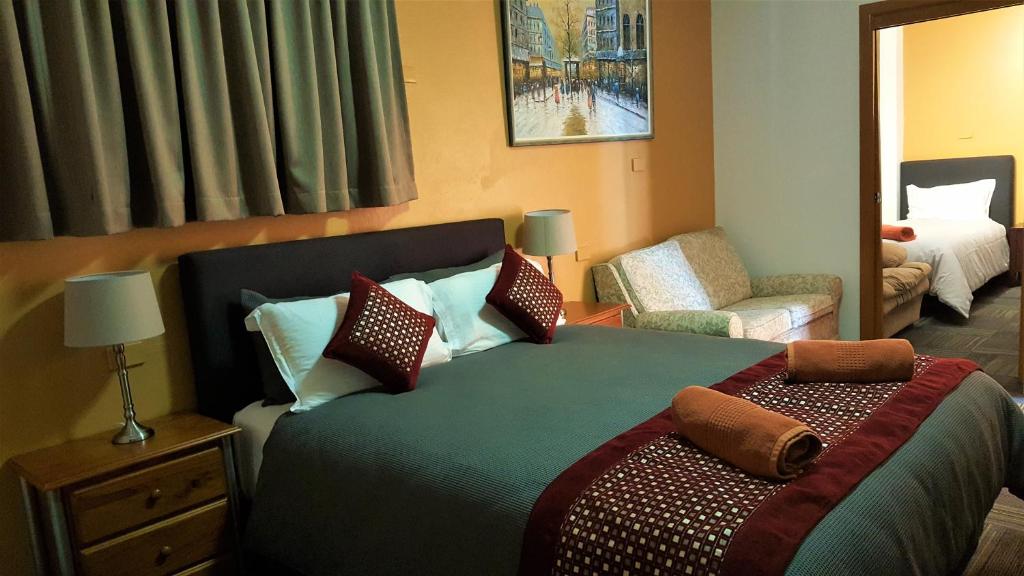 a bedroom with a bed and a couch and a chair at New Olympic Motel in Lismore