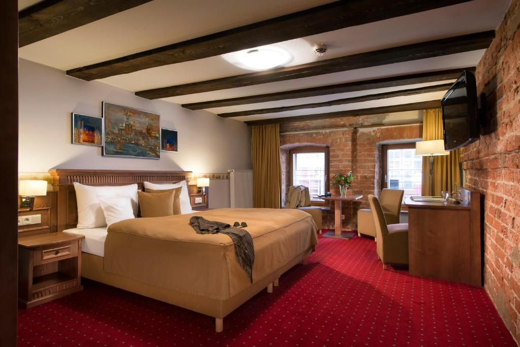 ein Hotelzimmer mit einem Bett, einem Schreibtisch und einem Stuhl in der Unterkunft Romantik Hotel Scheelehof Stralsund in Stralsund