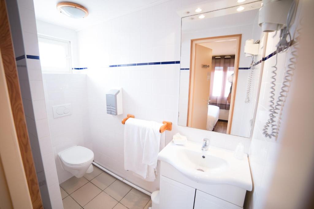 a white bathroom with a sink and a toilet at Hotel Atlantique in Mimizan-Plage