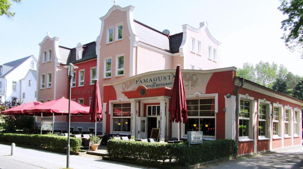 a red and white building with a restaurant on the street at Hotel Ostseestern in Kühlungsborn