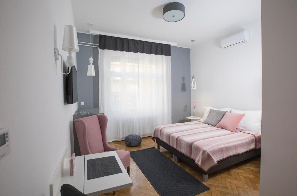 a bedroom with a bed and a couch and a window at Dóm Apartman in Szeged