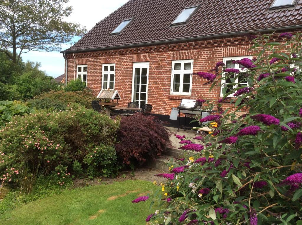 Axelgaard Guest Rooms في Ovtrup: منزل من الطوب مع الزهور أمامه