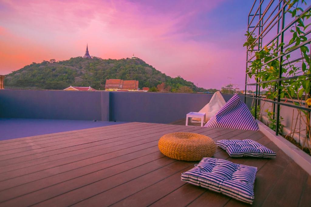 einen Balkon mit einem Tisch und Kissen auf einer Terrasse in der Unterkunft Chedi View Hostel in Phetchaburi