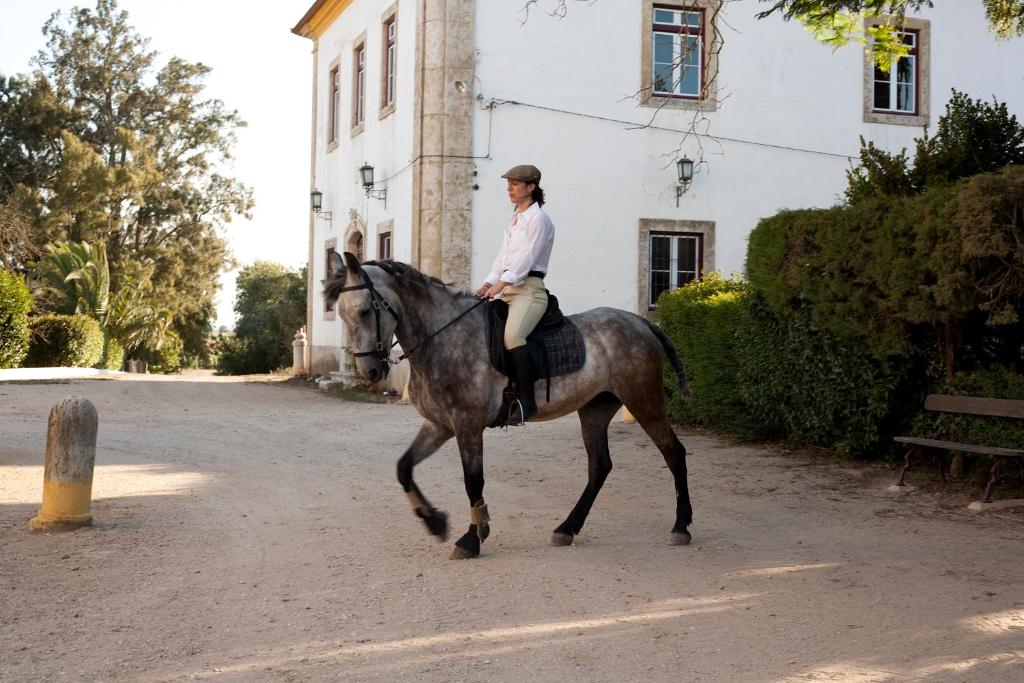 Eine Frau, die vor einem Gebäude reitet in der Unterkunft Quinta dos Álamos Agroturismo in Golegã