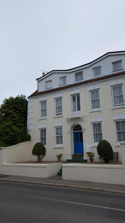 biały budynek z niebieskimi drzwiami na ulicy w obiekcie Franklyn Guesthouse w mieście Saint Helier