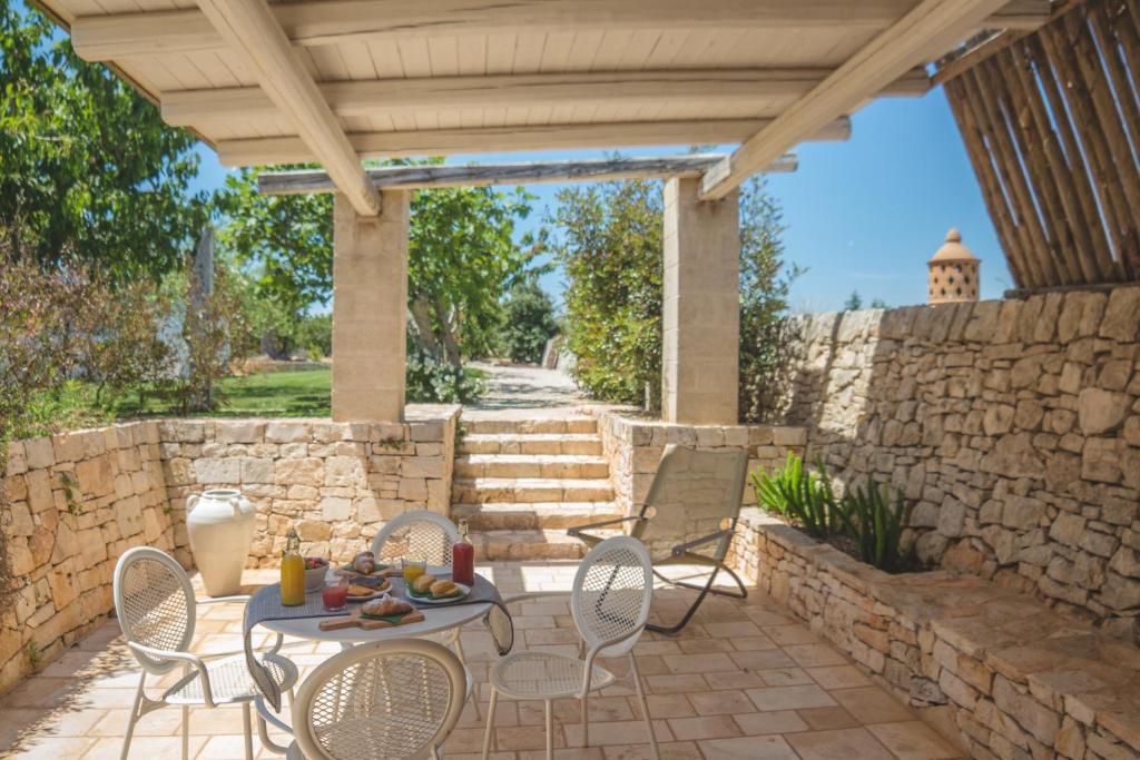 un patio avec une table et des chaises et un mur en pierre dans l'établissement Masseria Rosa Trulli Relais, à Alberobello