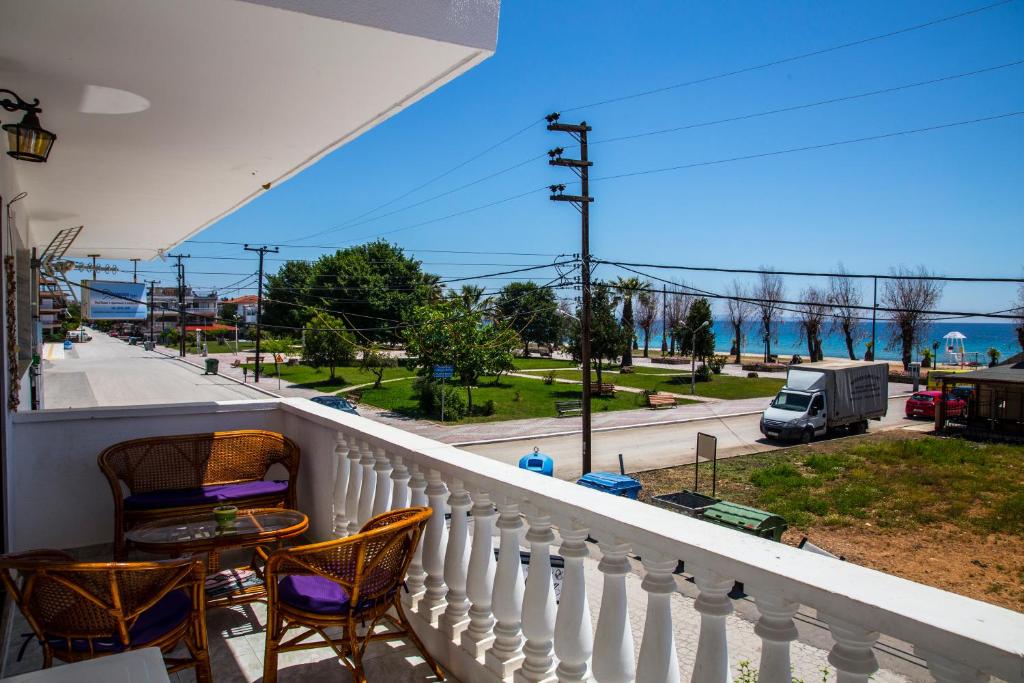 a balcony with chairs and a table and a view of a street at Park Apartment in Paralia Dionysiou