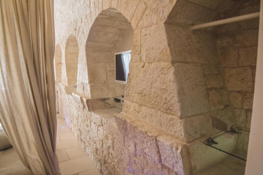 un mur de pierre dans une salle de bain avec une fenêtre dans l'établissement Masseria Rosa Trulli Relais, à Alberobello