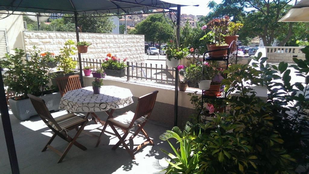 eine Terrasse mit einem Tisch, Stühlen und Topfpflanzen in der Unterkunft Apartments Dalia House in Hvar