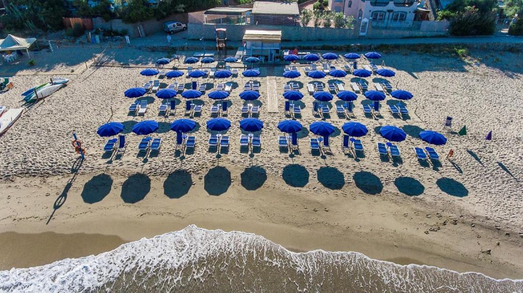 eine Gruppe von Sonnenschirmen und Stühlen am Strand in der Unterkunft Hotel Ulisse in Palinuro