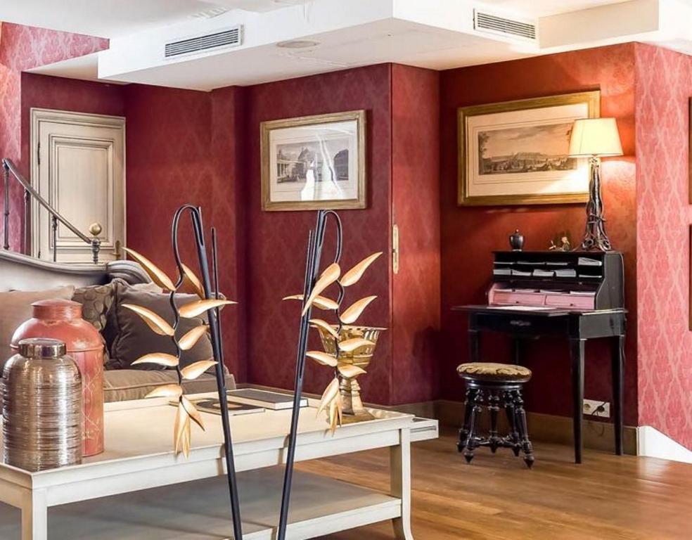 a living room with red walls and a piano at Hôtel du Romancier in Paris
