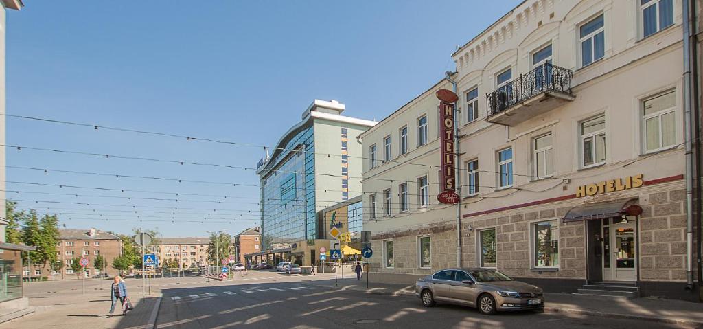 a car is parked on a city street with buildings at Saules rati in Daugavpils