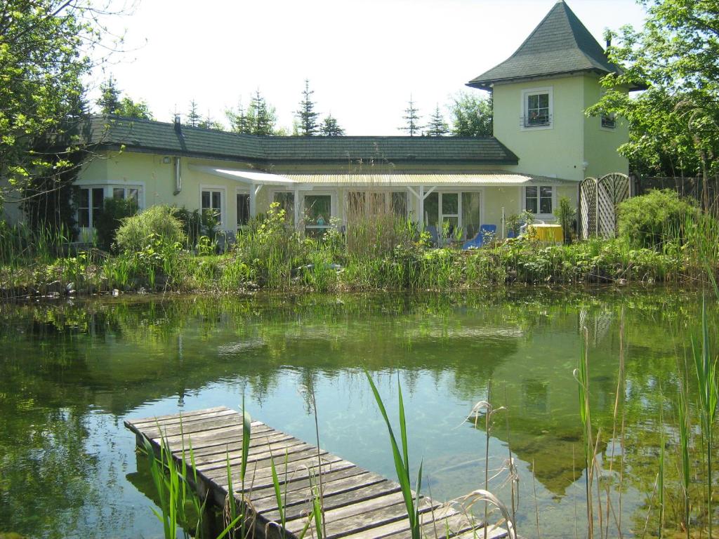 een huis met een vijver ervoor bij Gasthaus Eggerberg in Neumarkt am Wallersee