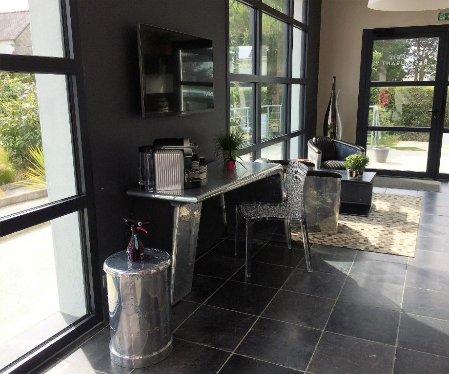 a living room with a table and chairs and windows at Hotel-Restaurant Lann Roz / Côte Cuisine in Carnac