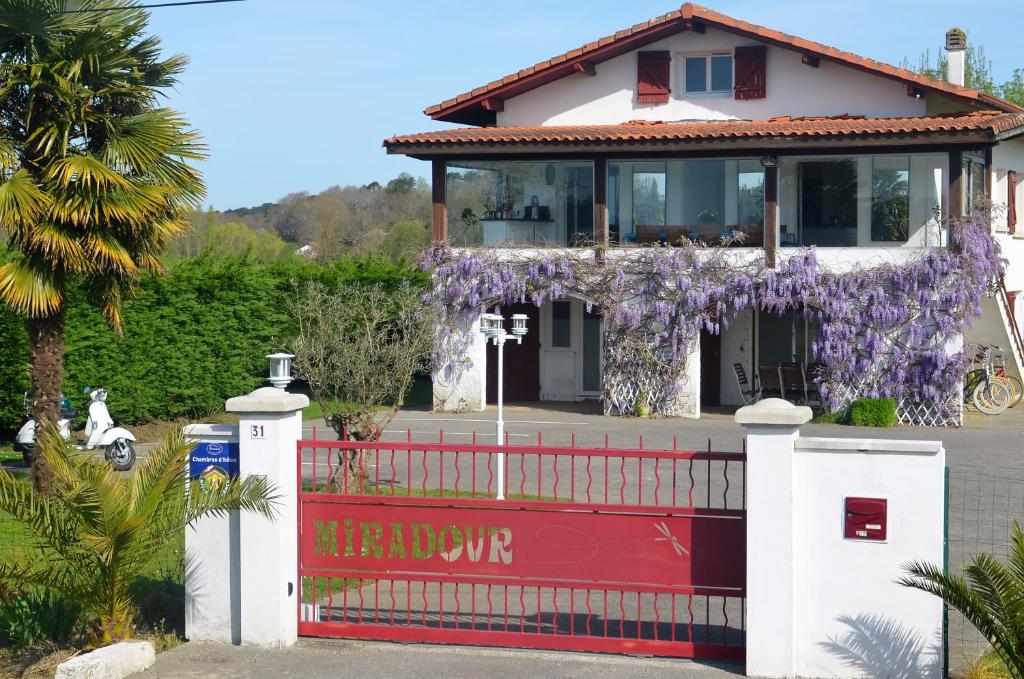 ein Haus mit einem roten Zaun mit einem Kranz lila Blumen in der Unterkunft Maison d'hôtes MIRADOUR in Tarnos