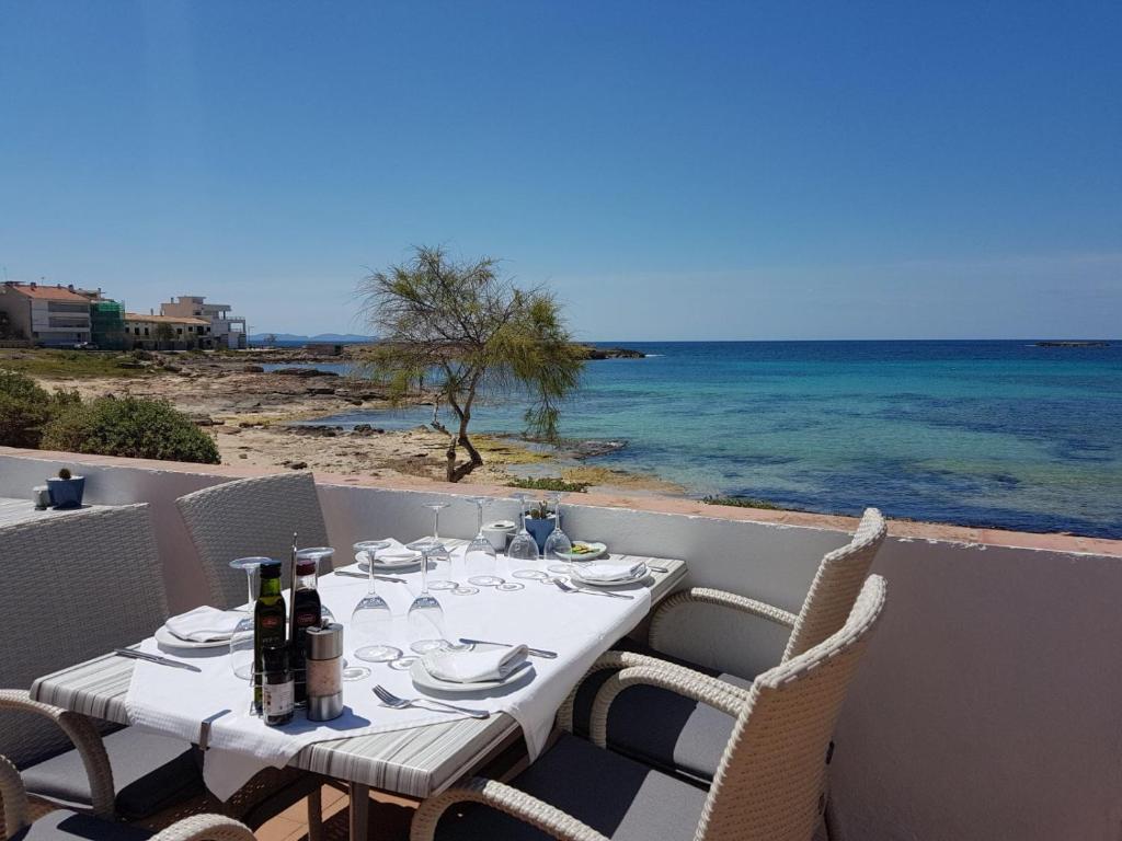 a table with chairs and wine bottles on the beach at Hostal Restaurante Playa in Colònia de Sant Jordi