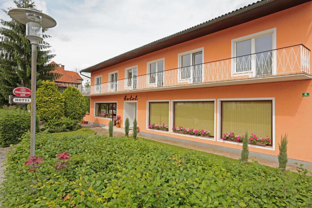 an orange building with a balcony and flowers in a yard at Hotel Reineldis in Mureck