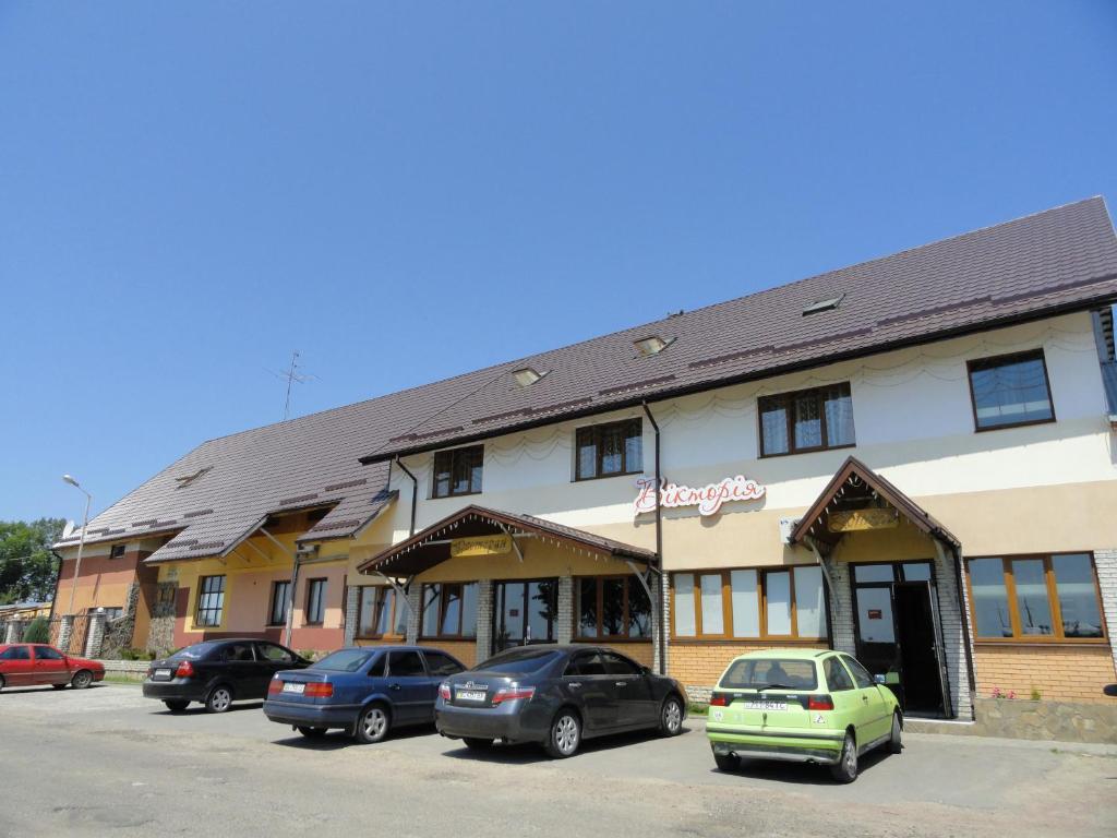 een gebouw waar auto's voor geparkeerd staan bij Viktoria Hotel in Obroshino