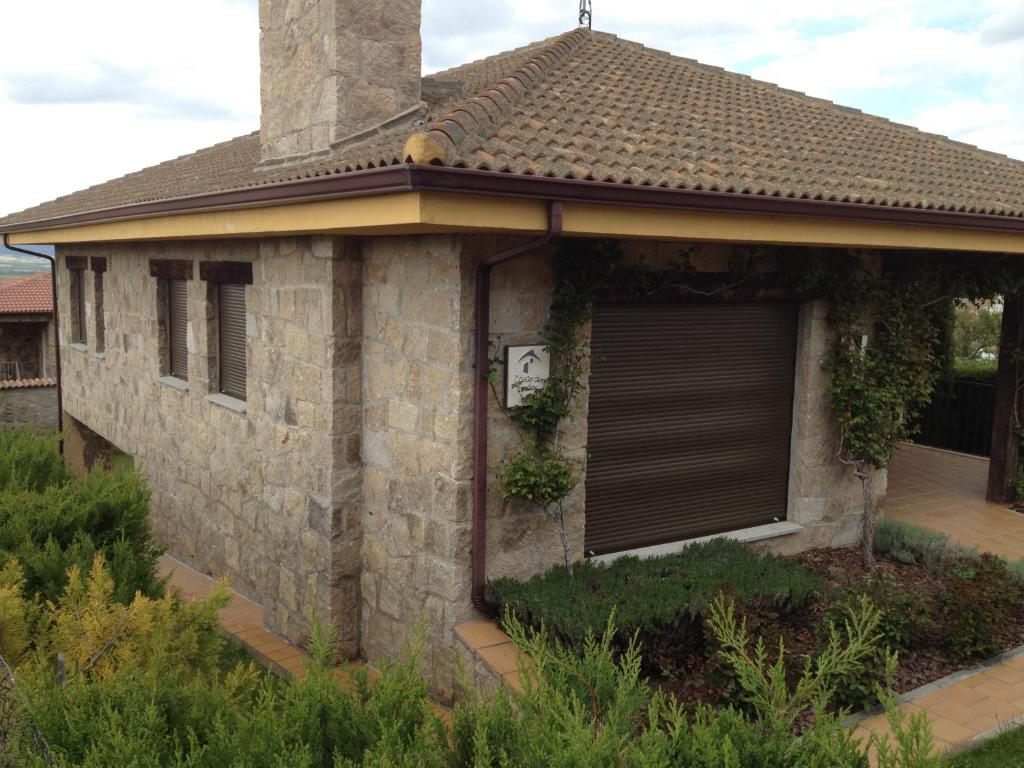 een stenen huis met een raam en een garage bij Casa Pico Zapatero in Sotalbo