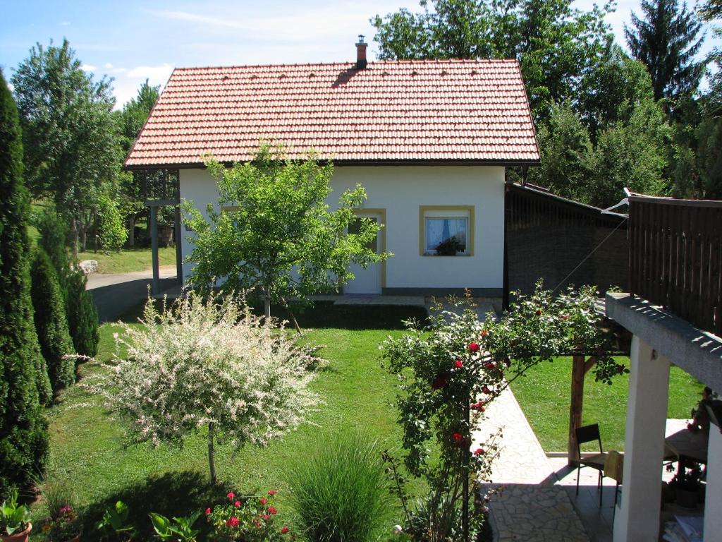 una pequeña casa blanca con un patio con flores en Apartment Ilija, en Rakovica