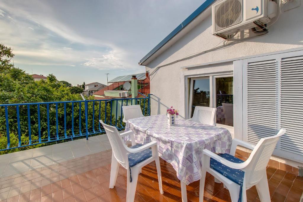 a dining table and chairs on a balcony at Apartment Malvina in Mali Lošinj
