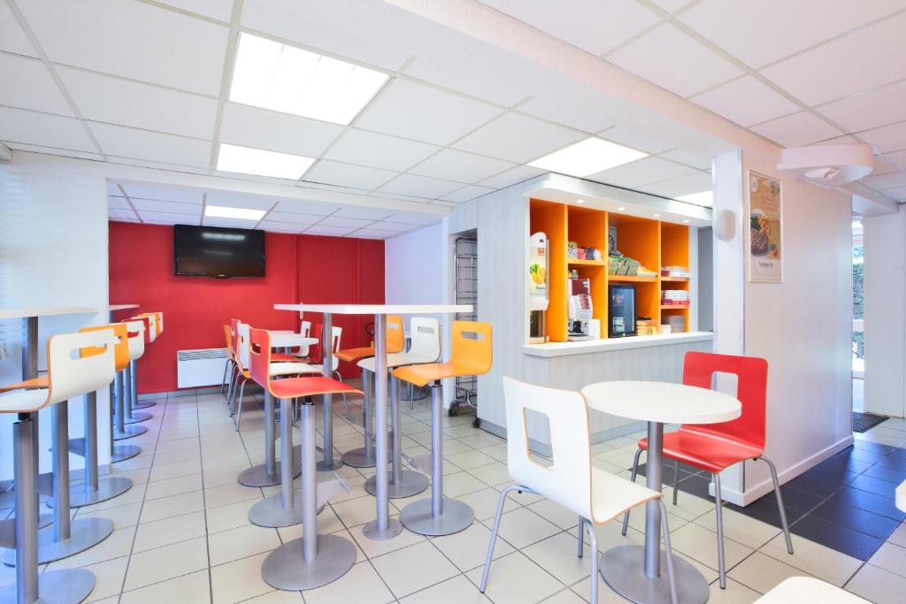 a restaurant with tables and chairs and a tv at Premiere Classe Bordeaux Eysines in Eysines