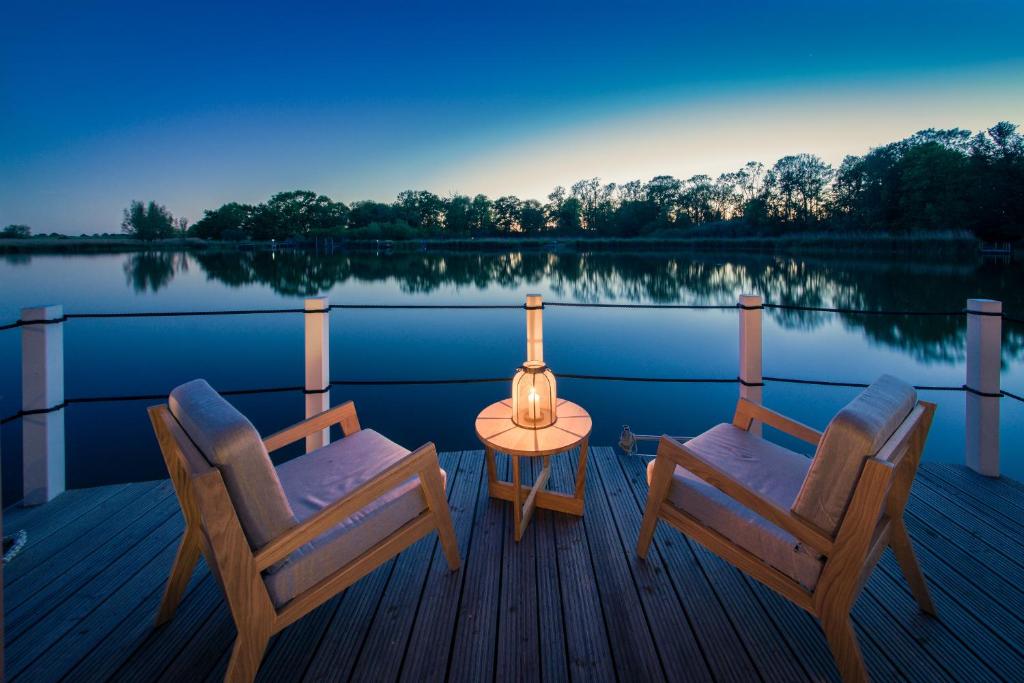 una terraza con 2 sillas y una mesa en un lago en Schwimmende Suiten Usedom, en Krummin