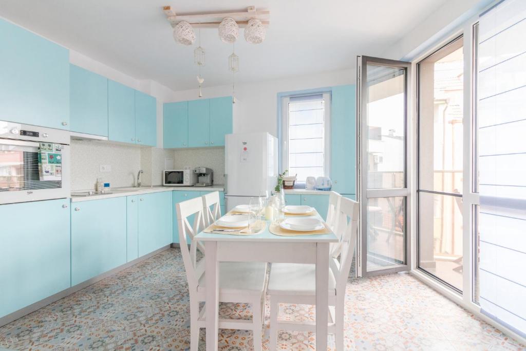 een keuken met een witte tafel en blauwe kasten bij Domus Apartments City Center in Plovdiv