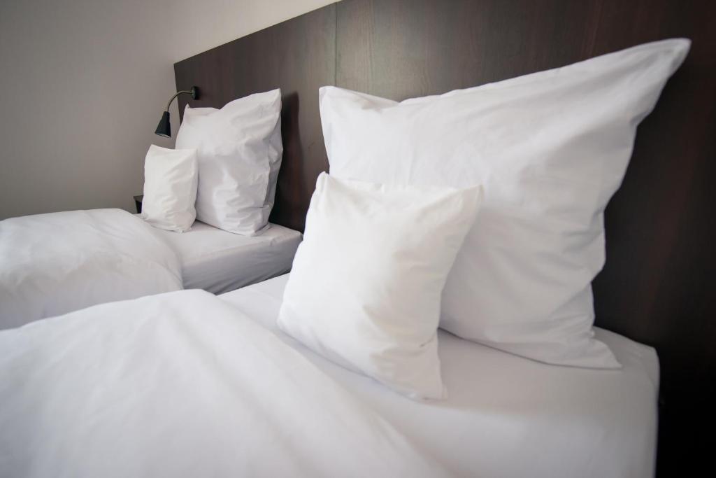 twee bedden met witte lakens en kussens bij First Hotel in Tczew