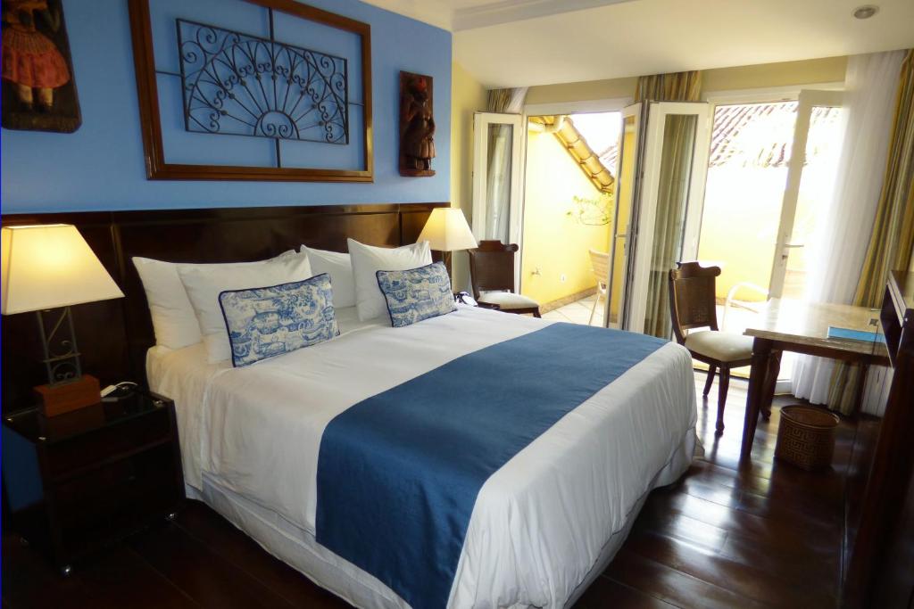 a bedroom with a large bed with a blue wall at Hotel Casa do Amarelindo in Salvador