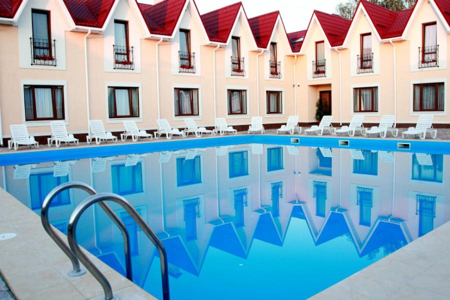 a hotel with a swimming pool with chairs and a building at Knyazhyi Dvir in Knyazhichi