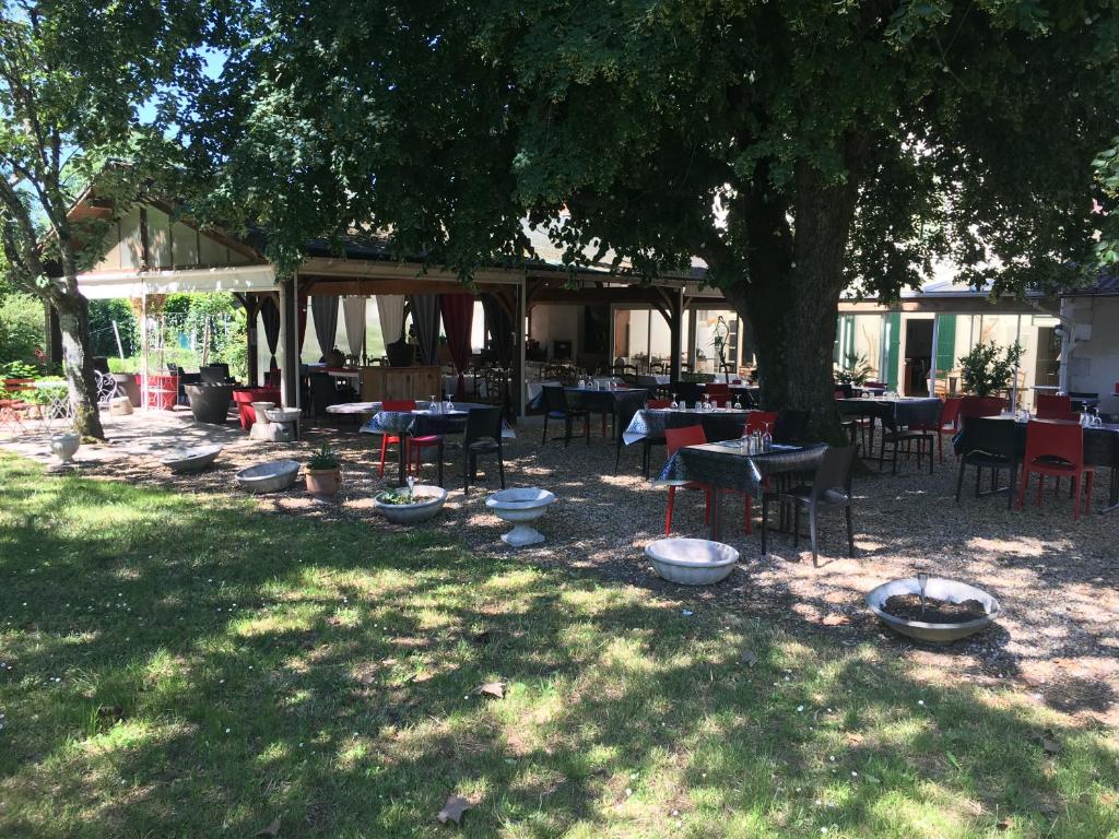 een restaurant met tafels en stoelen onder een boom bij L'Art Dit Vin in Saint-Aigulin