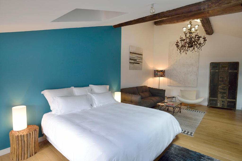 - une chambre avec un grand lit blanc et un mur bleu dans l'établissement Les Apparts du Plot, au Puy-en-Velay