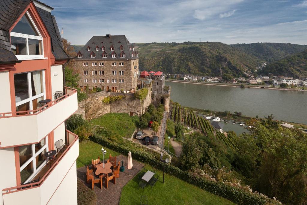 a castle on a hill next to a body of water at Hotel Schloss Rheinfels in Sankt Goar