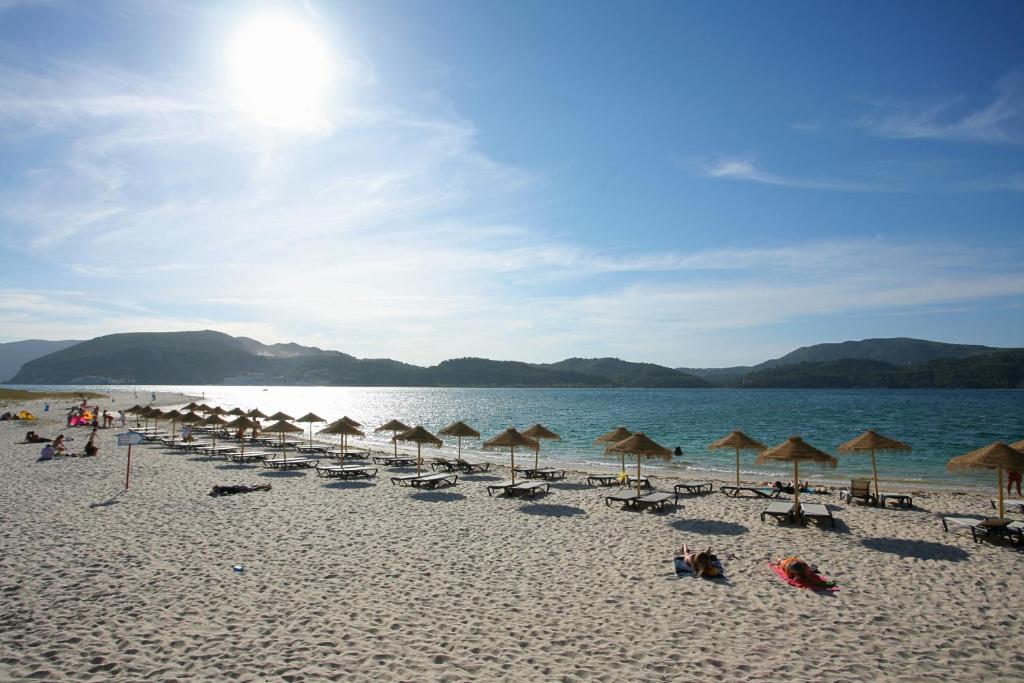 a beach with many chairs and umbrellas and the ocean at Troia Residence by The Editory - Apartamentos Marina in Troia