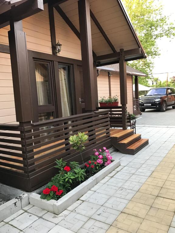 Una casa con un porche con flores. en Guest House na Vozba 9A, en Gudauta