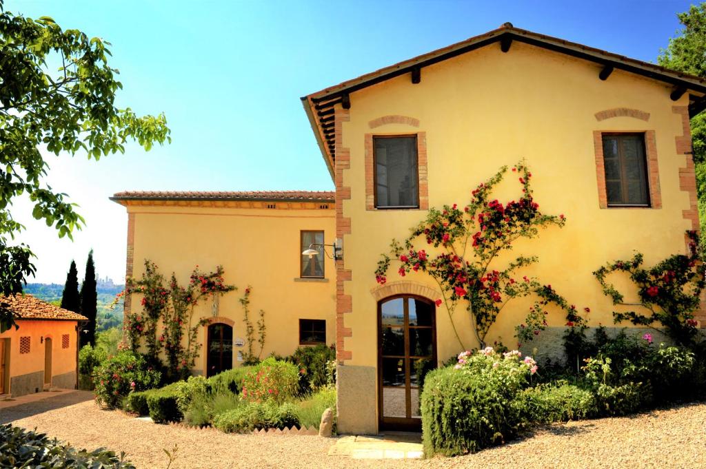 duży żółty dom z kwiatami przed nim w obiekcie Agriturismo Il Segreto di Pietrafitta w mieście San Gimignano