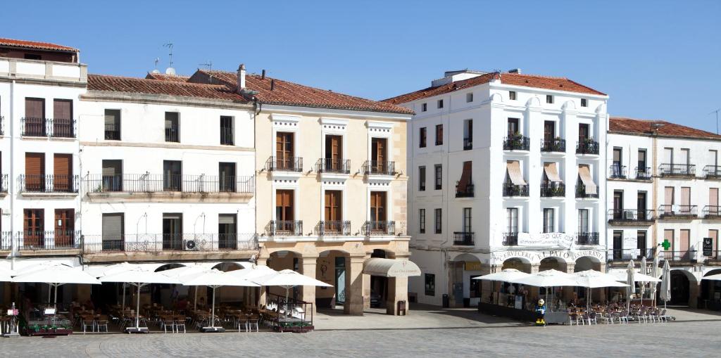 un grupo de edificios con mesas y sombrillas en Soho Boutique Casa Don Fernando, en Cáceres