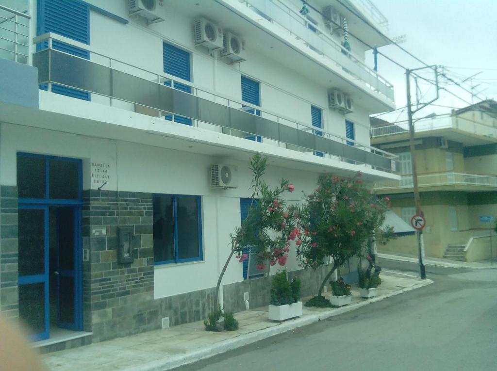 a building with blue windows and plants on the side of it at Pension Gina in Methana