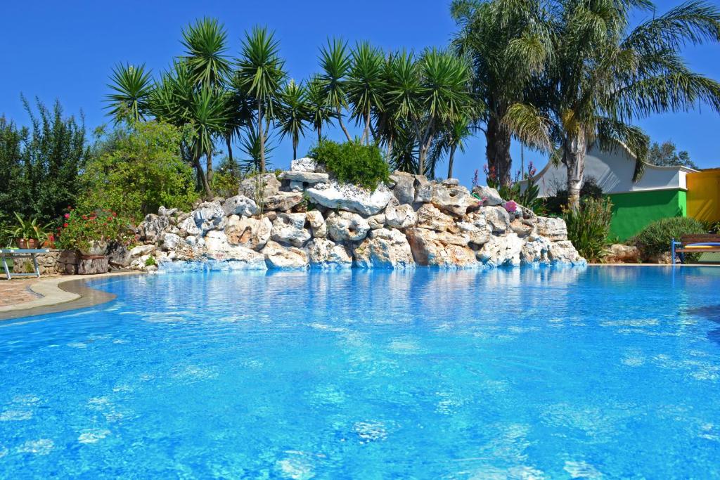 a large swimming pool with a rock wall at Villa Vacanze Paradiso - Oasi di Tranquillità con Piscina e Giardino a 10 min dal mare in Neviano