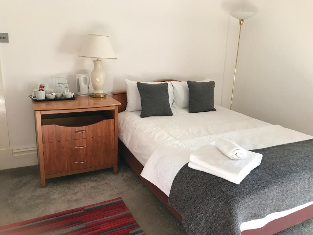 a bedroom with two beds and a night stand with a lamp at Haya Guest House in Birmingham