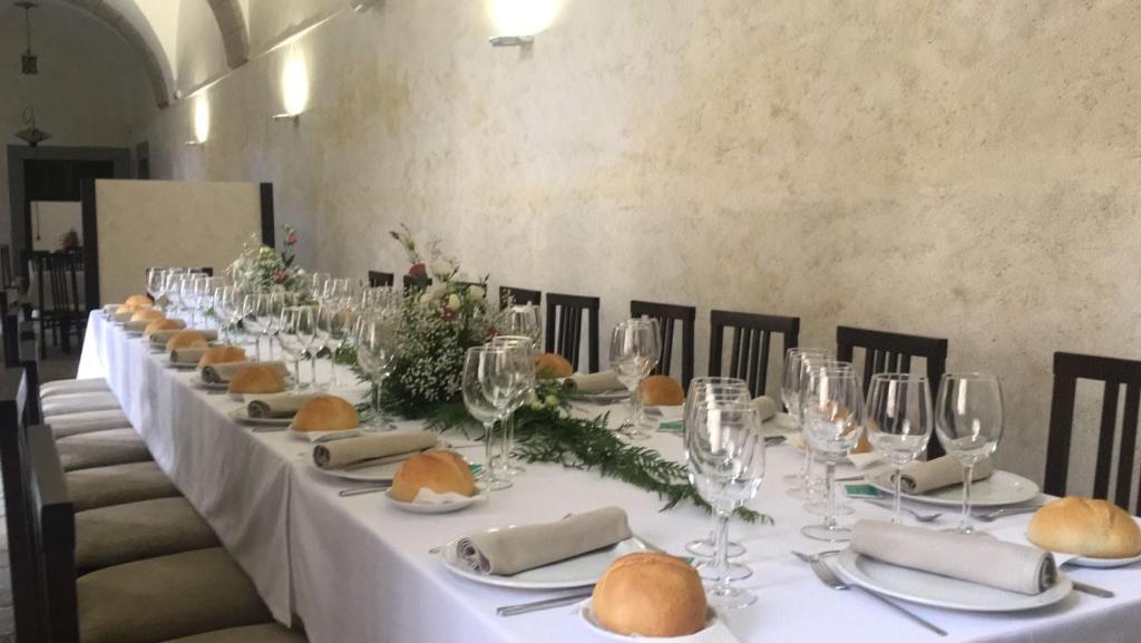 una mesa larga con copas de vino y pan. en San Nicolas el Real, en Villafranca del Bierzo