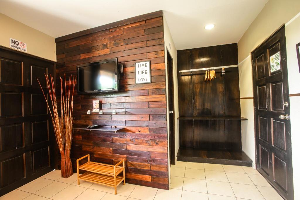 Habitación con pared de madera y TV. en Manglar Lodge, en San Carlos