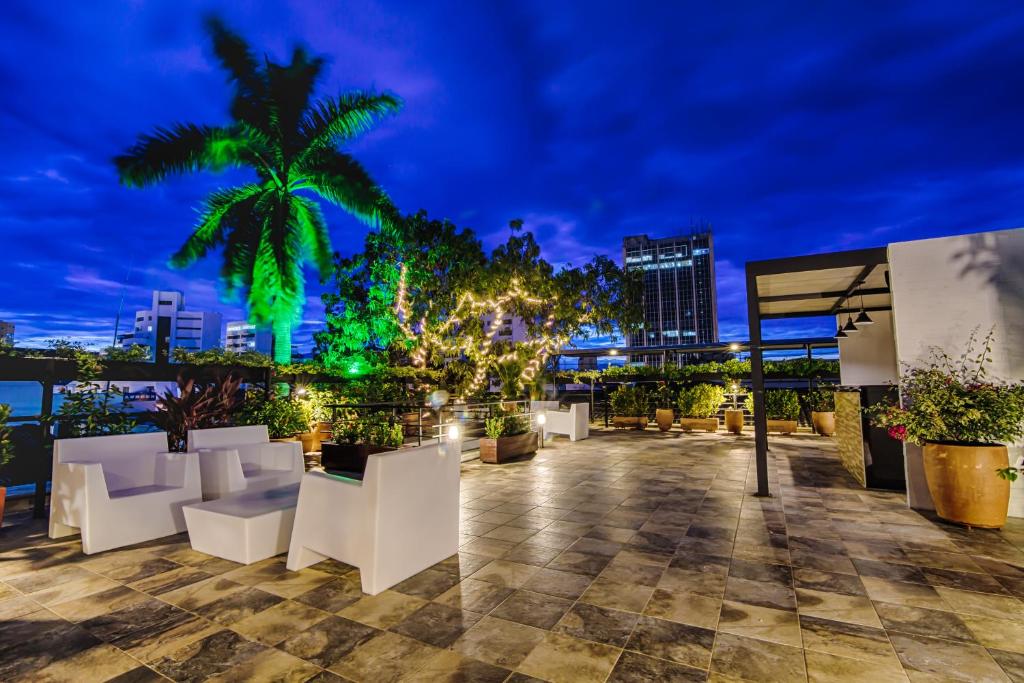 a rooftop patio with white furniture and a palm tree at night at Hotel Rosales Boutique in Neiva